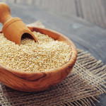 Raw quinoa seeds in the wooden bowl on wooden background closeup